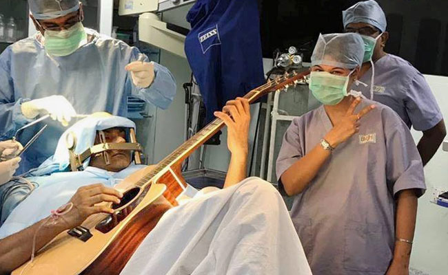 Man plays guitar in operation theater during brain surgery