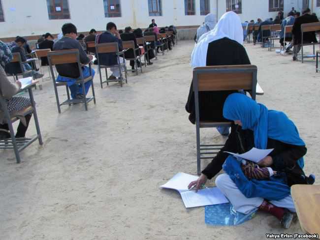 Afghan woman cradling baby during university exam
